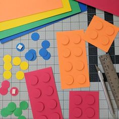 some construction paper and scissors are laying on the floor next to legos that have been cut out