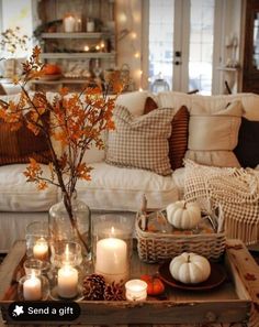 a living room filled with lots of white furniture and candles on top of a coffee table