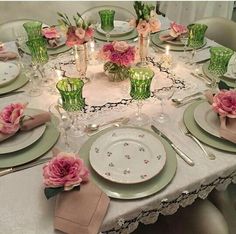 the table is set with pink flowers and place settings