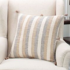 a white chair with a striped pillow on it's back and a wooden table in the background