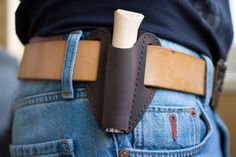 a person wearing a leather belt with a knife in the back pocket on his jeans