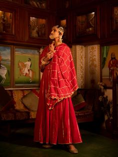 Enter the world of luxurious & regal clothing with Sahiba. Celebrate the grandeur of beauty, celebrations, dressing up and womanhood with vintage textiles and silhouettes. Set of 3 consists of Kalidar, pajama and dupatta. Kurta: A red ghera cotton kalidar is adorned with heavy gold gota work on neck and kalis. Dupatta: A handspun mul red dupatta is detailed with zari and mirror scallop detailing with heavy gota chaukadi work Bottom: Red Farshi pajama is detailed with pure metal gold lampi. Mater Semi-stitched Floor-length Anarkali Set For Traditional Ceremonies, Elegant Kurta With Traditional Drape For Ceremonies, Elegant Traditional Drape Kurta For Ceremonies, Festive Ceremonial Cutdana Dresses, Unstitched Anarkali Set For Traditional Ceremonies, Floor-length Salwar Kameez For Navratri, Floor-length Salwar Kameez With Pallu For Traditional Ceremonies, Floor-length Salwar Kameez For Navratri Ceremonies, Unstitched Floor-length Anarkali Set For Traditional Ceremonies