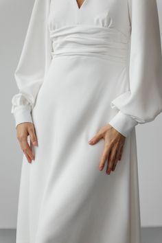 a woman in a white dress with her hands on her hips