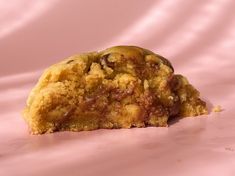 a close up of a cookie on a pink surface with a bite taken out of it