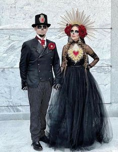 a man and woman dressed up in costume for the day of the dead, standing next to each other