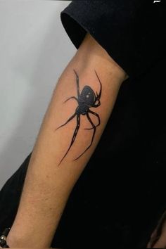 a black spider tattoo on the arm