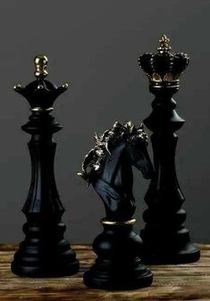 two black chess pieces with gold accents on them, one is king and the other is queen