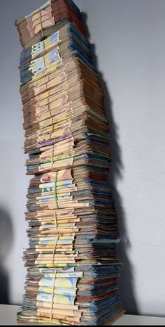 a large stack of papers sitting on top of a table next to a white wall