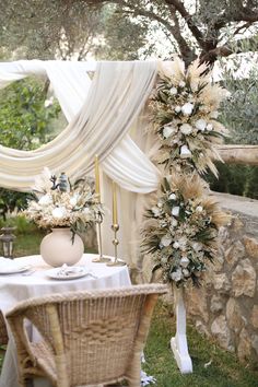 an outdoor table set up for a wedding reception with flowers and greenery in vases