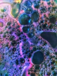 some water bubbles are on the surface of a liquid filled with colored liquids and blue, green, yellow, purple, and pink colors