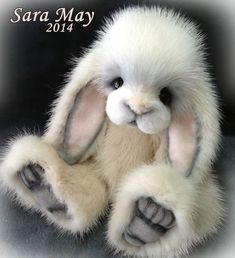 a white stuffed rabbit sitting on top of a gray floor next to a black background