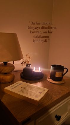 an open book on a table next to a lit candle and a cup with tea