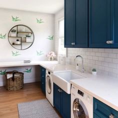 a washer and dryer in a small room with blue cabinets, white counter tops and wooden floors