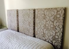 an upholstered headboard on a bed in a room with a white comforter