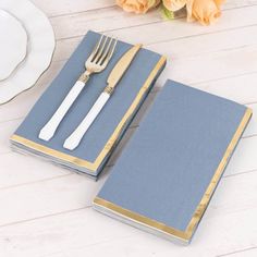 two silverware sitting on top of a blue book next to a fork and knife