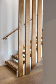 a wooden stair case next to a white wall