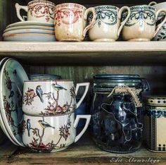 some jars and bowls are sitting on the shelf in front of each other with birds painted on them