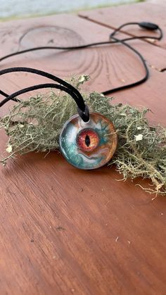 This handcrafted dragon eye necklace is a unique piece that is sure to be a statement pieces. I created this epoxy resin necklace with a glass faux eye that I have encased in eco epoxy resin. The background is swirled copper, hunter green, and white colored epoxy resin. This pendant will make a special gift for him. -Pendant Sizing- 1 inch diameter  -This pendant includes a pull apart clasp corded necklace-  -Necklace can be sized from 16-24 inches- -All necklaces include a small necklace box or Hand Painted Spiritual Resin Jewelry, Adjustable Resin Round Pendant Necklace, Mystical Resin Necklaces For Gifts, Unique Eye-shaped Jewelry For Gifts, Handmade Mystical Resin Jewelry, Dragon Eye Necklace, Epoxy Resin Necklace, Colored Epoxy Resin, Evil Eye Choker