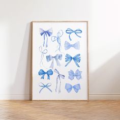 an art piece with blue bows on it in front of a white wall and wooden floor