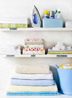 the shelves are filled with folded towels and other household items, including an ironing board