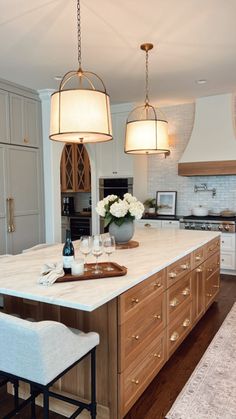 a large kitchen with an island in the middle and two pendant lights hanging from the ceiling