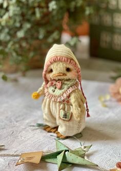 a small figurine of a chicken wearing a knitted hat and scarf sitting on a table