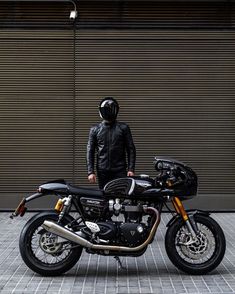 a man standing next to a motorcycle on a brick road in front of a garage door