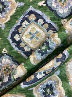 the fabric is green with blue and yellow flowers on it, as well as an ornate design