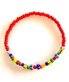 "Colorful African \"Love\" beads mixed with bright red white heart glass beads and Karen Hill Tribe fine silver on a skinny stretch bracelet. These colorful skinny bracelets are trending now in Europe for both men and women! Fun for summer! The 3-4mm multicolored vintage Czech glass beads are handmade in varying sizes and shapes. Originally made to be sent to Africa. The bright red handmade African glass beads are from Ghana and are called \"white heart\" beads because of the pure white painted Red Beaded Bracelets With Letter Beads For Beach, Red Beaded Bracelets With Heart Beads For The Beach, Red Glass Beaded Bracelets With Round Beads, Adjustable Red Stretch Bracelet With Heart Beads, Red Letter Beads For Gifts, Adjustable Red Beads With Large Beads, Red Beaded Bracelets With Colorful Beads For Beach, Red Beaded Bracelet With Colorful Beads For Beach, Adjustable Red Large Beads