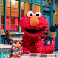 the sesame street character is sitting at a table with candy and candies in front of him