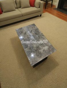 a marble coffee table in the middle of a living room with a couch behind it