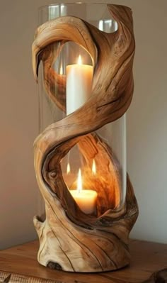 two candles are in a glass vase with wood carvings on the sides and inside it