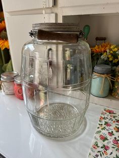 a glass teapot sitting on top of a counter next to flowers and other items