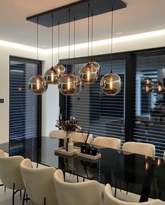 a dining room table with chairs and lights hanging from the ceiling