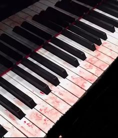 an old piano with blood all over it's sides and the keys are black