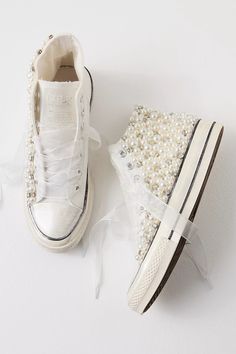 a pair of white sneakers with pearls on them