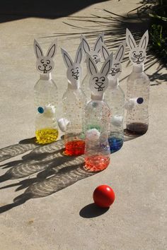 plastic bottles with bunny ears are lined up next to an orange ball on the ground