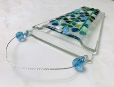 a glass piece with blue and green designs on it sitting on a white counter top