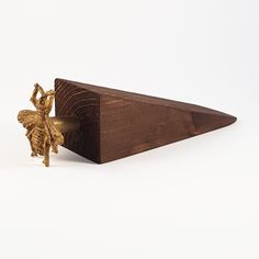 a gold bee figurine sitting on top of a piece of wood next to a white background