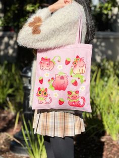 a woman carrying a pink tote bag with cats and flowers on it, in front of some plants