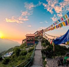 the sun is setting on top of a mountain with many colorful flags hanging from it