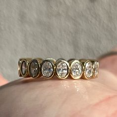 a close up of a person's hand holding a ring with five diamonds on it