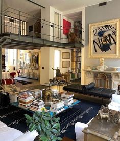 a living room filled with lots of furniture and books on top of a hard wood floor