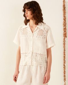 A person with curly brown hair wears the Stevie Picnic Eyelet Shirt Summer Floral Embroidered Top With Spread Collar, Summer Top With Floral Embroidery And Spread Collar, White Collared Bohemian Top, White Bohemian Collared Shirt, White Bohemian Collared Top, Bohemian White Collared Top, Spring Bohemian Tops With Camp Collar, Bohemian Spring Tops With Camp Collar, Bohemian Camp Collar Tops For Spring