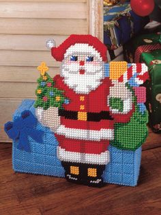 a cross stitch santa clause holding a christmas tree