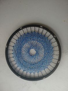 a blue and black circular object hanging on the wall with strings in it's center