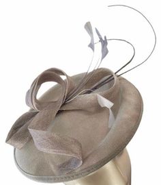 A stunning silver grey coloured sinamay flower fascinator comprised of a sinamay base, loops of sinamay in the same gorgeous shade of silver colour and hand shaped feathers finished with a double quill. This fascinator sits securely on your head with a satin covered headband in a coordinating shade. A stunning addition to any outfit! Fascinator measures approx 26cm Headband measures 1cm wide Please note as our fascinators are hand dyed to order if you feel this colour may not be quite right please request to see a colour chart. If you would like the fascinator created in an alternative dye colour which we don't currently stock there will be a charge of £30 to cover the cost of the dye and the labour.  Our timeless pieces are perfect for any special occasion from Weddings to The Kentucky De Silver Hat Headpiece For Party, Silver Party Hat Headpiece, Elegant Silver Fascinator, Elegant Fitted Silver Fascinator, Elegant Silver Hat For Evening, Silver Hat With Curved Brim For Formal Occasions, Elegant Silver Hat For Kentucky Derby, Silver Fascinator Hat For Formal Occasions, Silver Fitted Fascinator For Evening