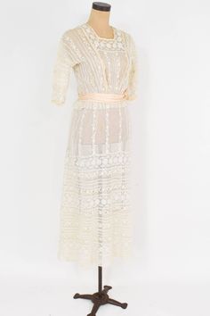 "~ 1900s beautiful tiered ivory lace sheer dress ~ Delicate pretty vintage dress ~ Perfect for a wedding dress ~ Sheer netting, insertion lace ~ 2 layer skirt ~ 28\" Peach satin waist sash ~ 2 \" peplum at waist ~ Back buttons and snaps Condition: Good but there are couple places with tiny holes. Priced accordingly Bust- 34\" (86.5 cm) Shoulder- 16.5\" (42 cm) Sleeve- 11\" (26 cm) Waist- 24\" (61 cm) Hips- 48\" (122 cm) Length Top skirt- 49\" (124.5 cm) Length under skirt- 51\" (129.5 cm) More I Cream Lace Dress With Patchwork For Garden Party, Delicate Cream Lace Dress, Cream Vintage Lace Dress With Lace Trim, Sheer Cream Lace Dress, Feminine Sheer Lace Dress For Wedding, Delicate Cream Dress With Lace Details, Delicate Cream Dress With Delicate Lace, Feminine Sheer Lace Wedding Dress, Delicate Cream Dress With Lace