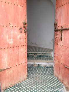 an open door leading to another room with green and white tiles