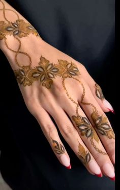 a woman's hand with hennap on it and gold leaves painted on it